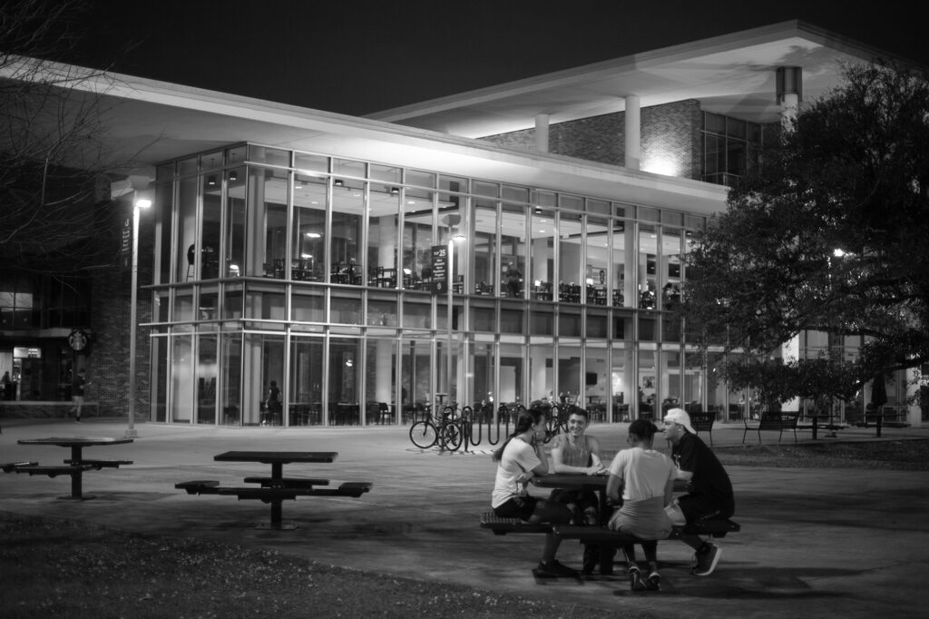 Students sit at a table in front of the new Student Union.